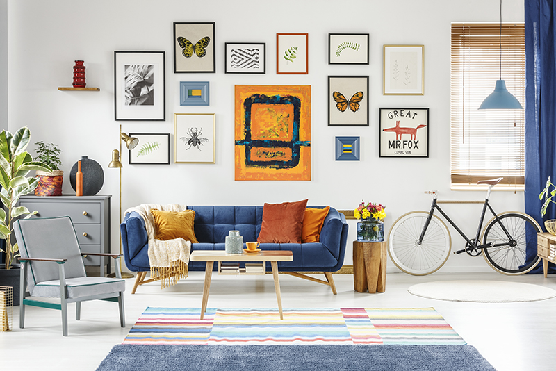 Grey armchair and blue sofa in spacious living room interior with posters and bicycle. Real photo